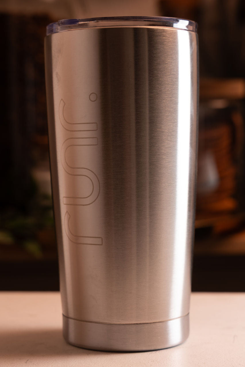 Stainless steel tumbler with 'Rus' branding on a wooden surface.